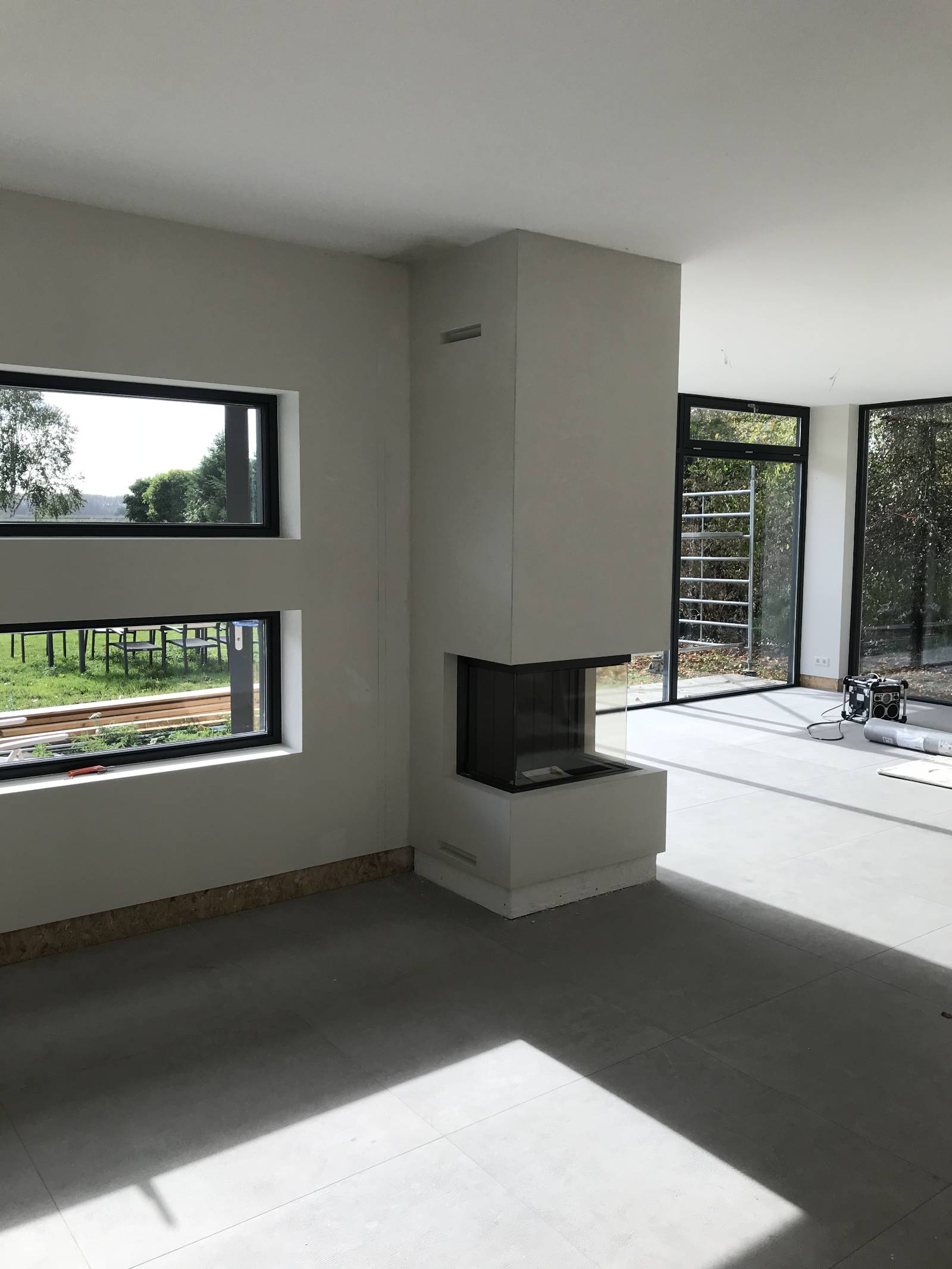 Lichte woonkamer met gestucte wanden en een haardkolom, werk van Corné’s Stukadoors